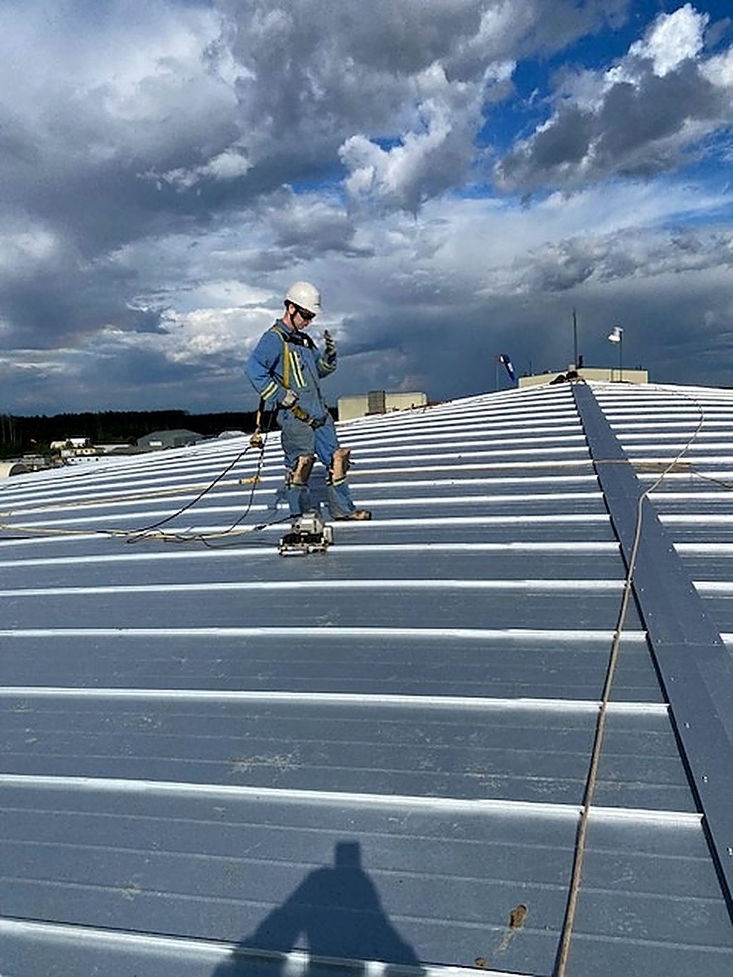 Installer closing standing seams on the new galvalume roof with a powered seamer