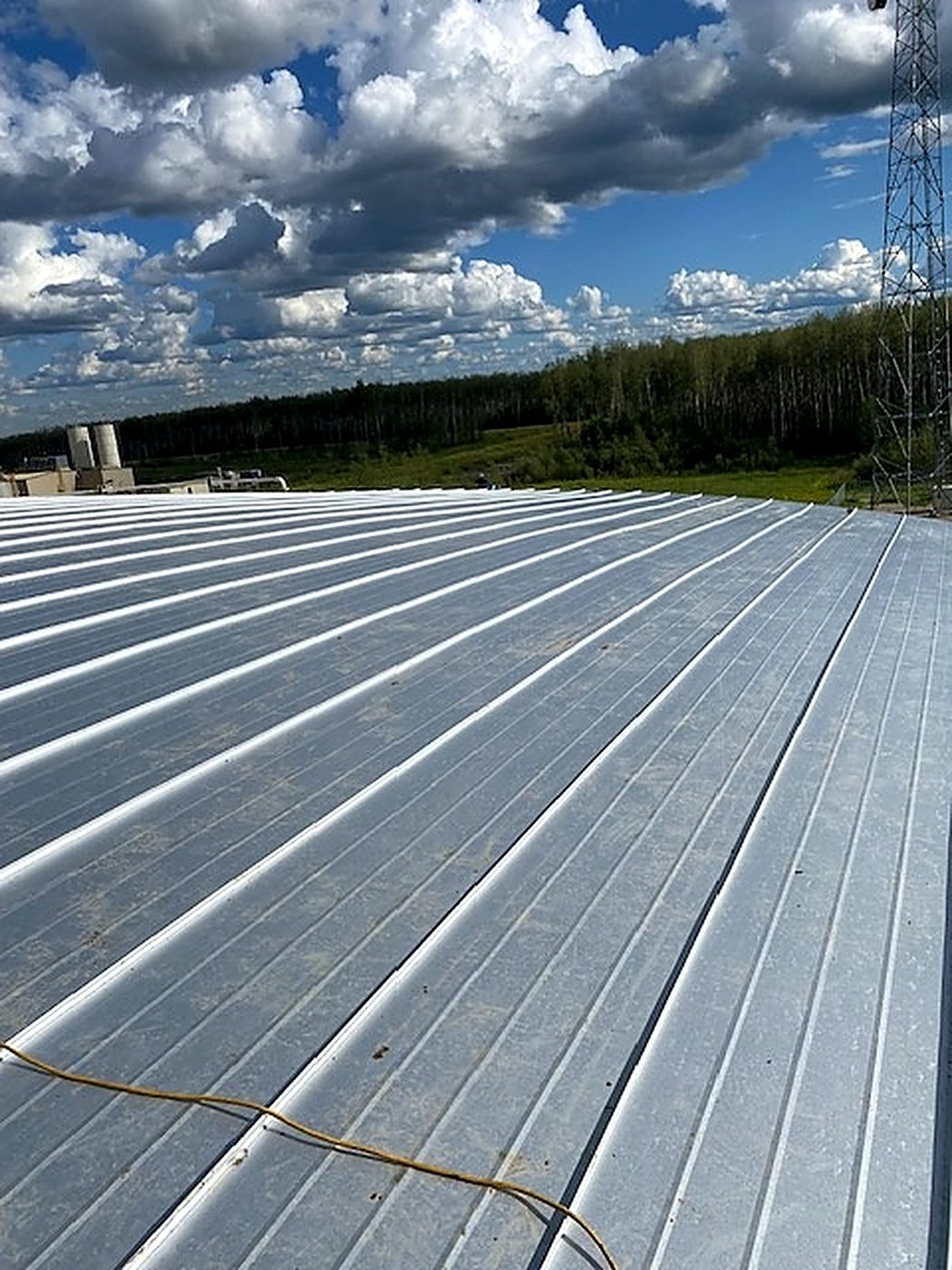 Completed galvalume standing-seam tank roof, continuous raised seams across the field