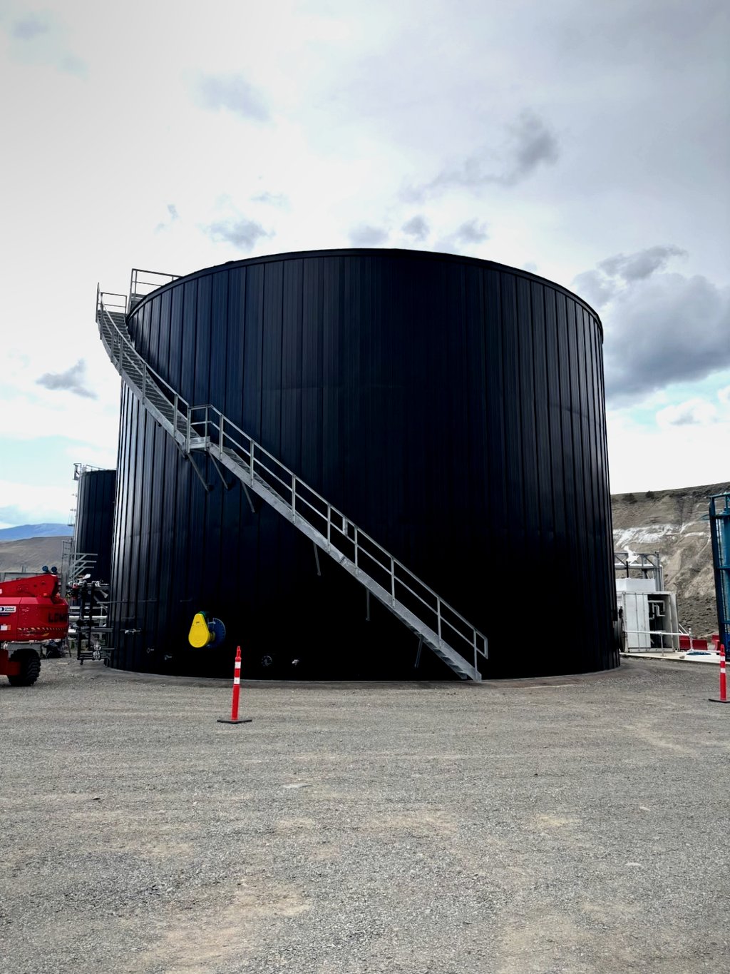 Black-finished pre-fabricated insulated tank with spiral access staircase, installed in British Columbia interior