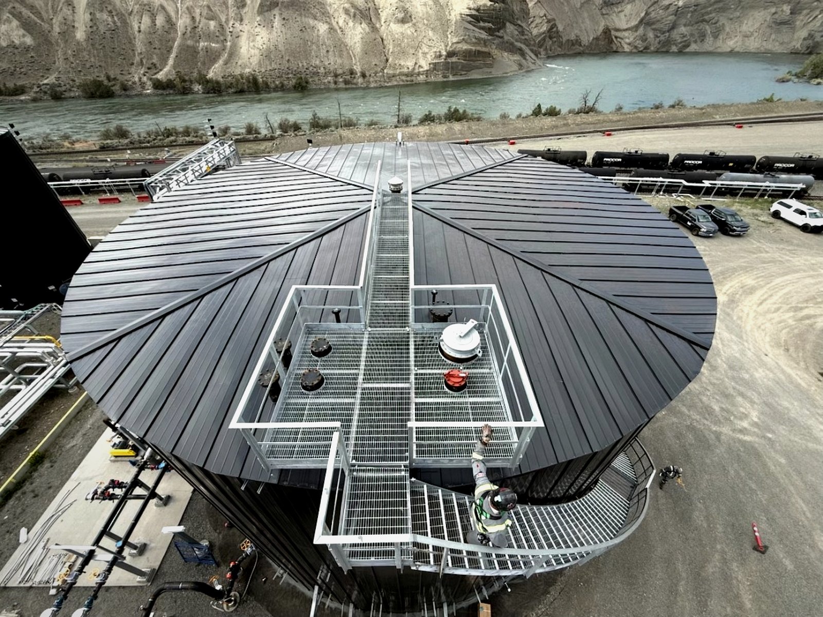 Aerial view of an insulated tank cone roof with the standing-seam pattern, river canyon backdrop