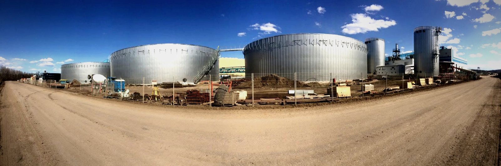 Industrial tank farm in Canada with pre-fabricated standing-seam insulated tanks under blue Alberta sky